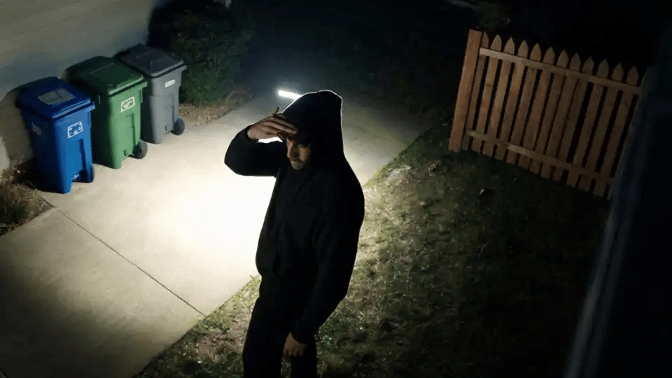 A person caught in the floodlight turns away