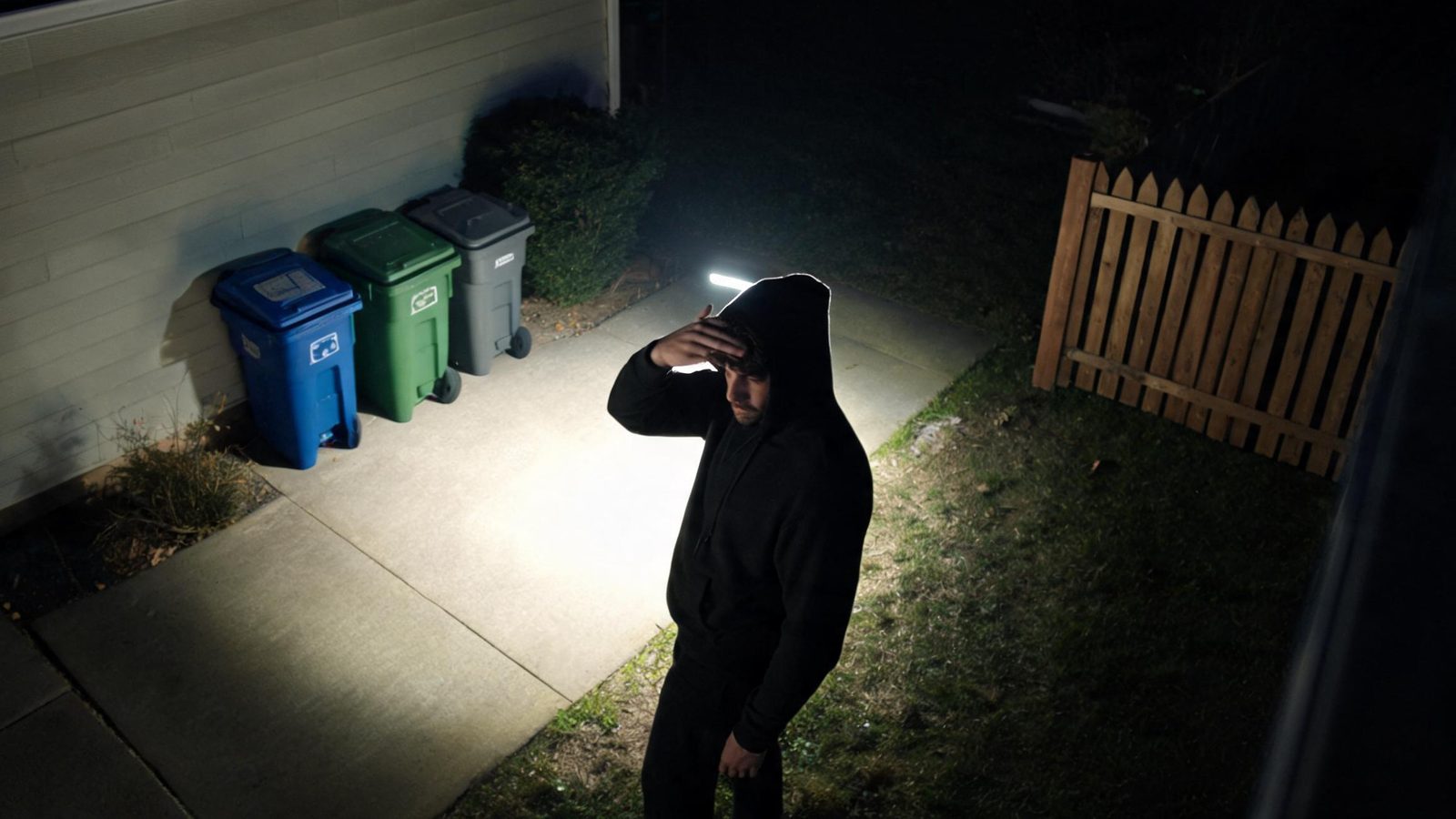 A person caught in the floodlight at a side gate