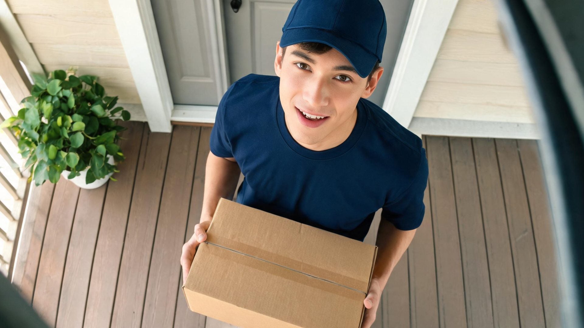 A courier holding a parcel looks up at the camera and talks
