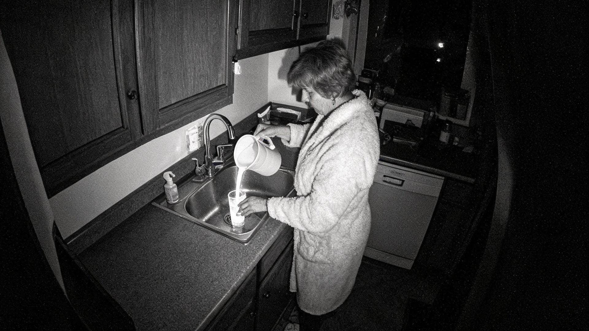 Night vision view of a woman pouring water at the kitchen sink